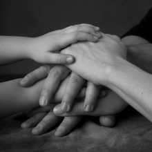 Hände, die aufeinander liegen und so den Zusammenhalt vieler symbolisieren